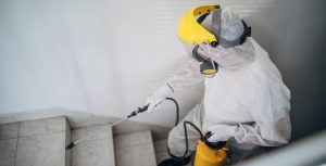 Man in protective suit disinfecting steps in building