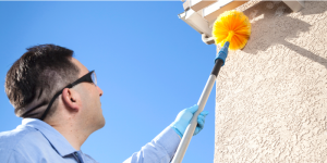 Cleaning spider cobwebs with a broom
