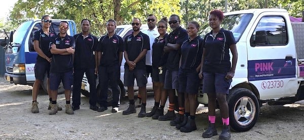 The Pink South Pacific team wearing dark T-shirts in front of their work vehicles