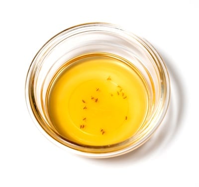 A small glass dish containing vinegar with some flies in it