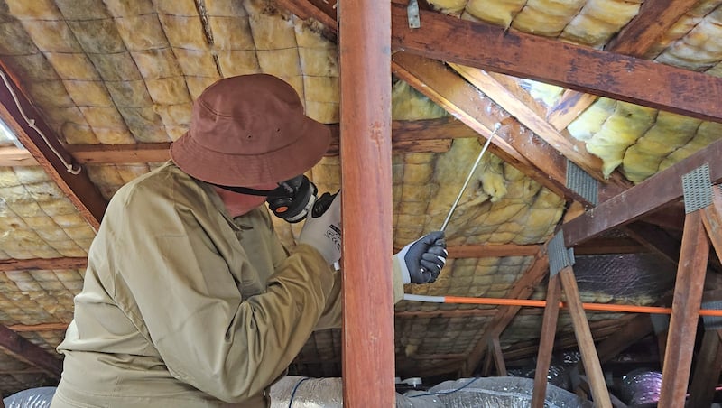 Pest inspector in a roof void wearing a hat