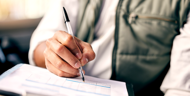 Man wearing a puffer vest and holding a pen