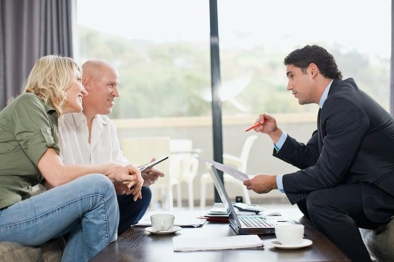 Couple sitting down speaking with a financial advisor or lawyer in a suit