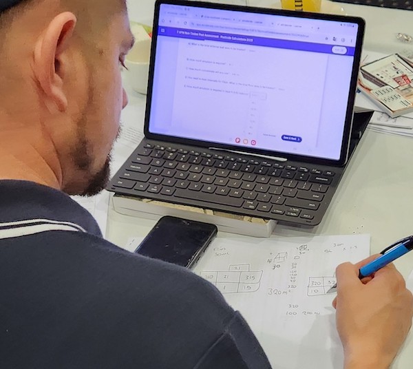 Man sitting at a computer holding a pen 
