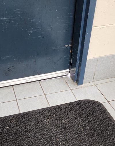 A navy blue door with a small gap at the bottom where insects could potentially enter