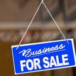 Blue sign in a window saying 'business for sale'