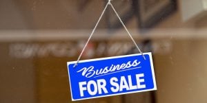 Blue sign in a window saying 'business for sale'