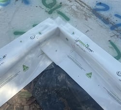 Two sheets of plastic meeting at a right angle as part of a building construction project