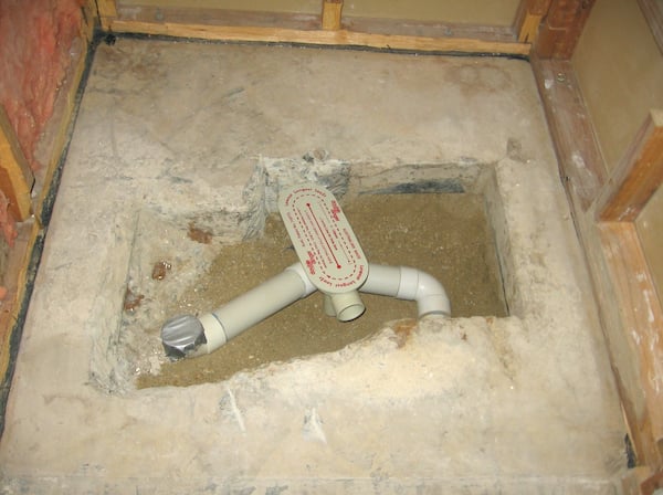 Plumbing pipes in an exposed bathroom floor