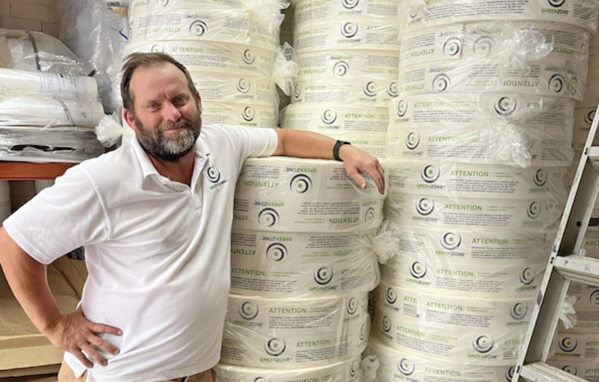 Brett Bowey from Greenzone leaning against Greenzone products in a warehouse